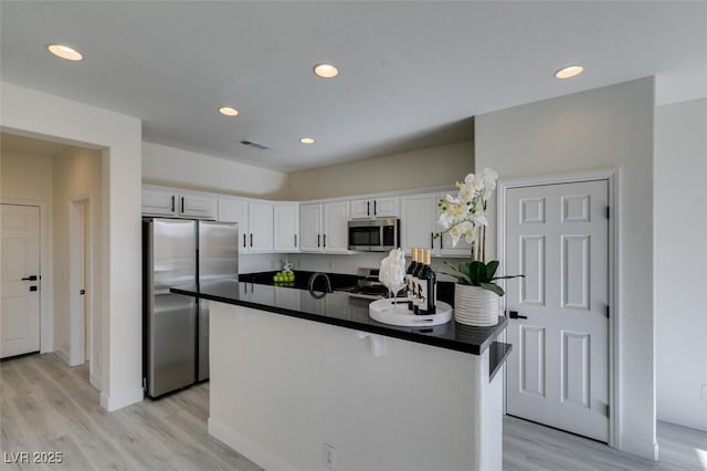 kitchen featuring appliances with stainless steel finishes, white cabinetry, light hardwood / wood-style floors, and a center island