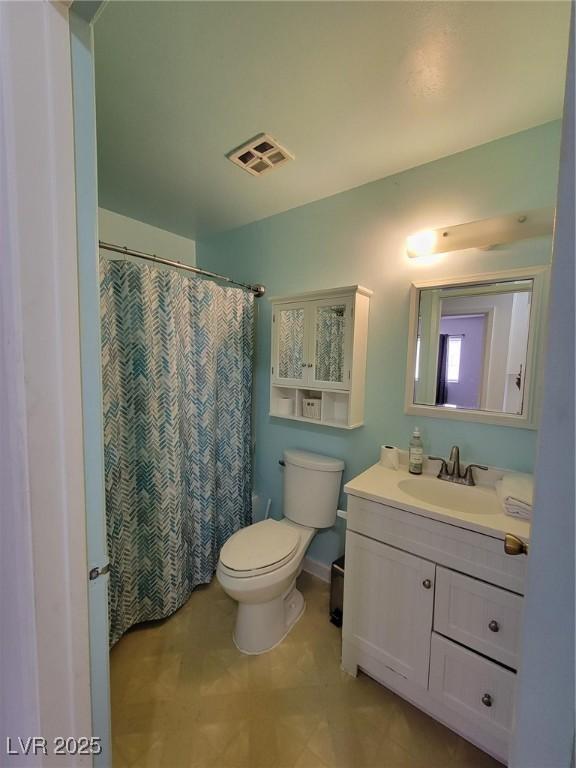 bathroom featuring toilet, vanity, and a shower with curtain