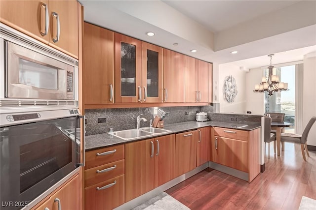 kitchen featuring decorative light fixtures, sink, backsplash, a notable chandelier, and stainless steel appliances