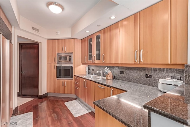 kitchen with sink, dark wood-type flooring, backsplash, stainless steel appliances, and kitchen peninsula