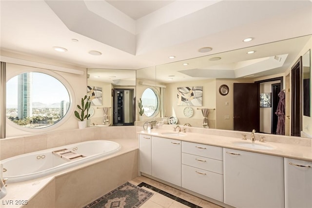 bathroom featuring a raised ceiling, vanity, tile patterned flooring, and tiled bath