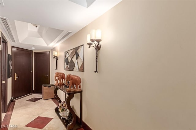 corridor featuring light tile patterned flooring and a raised ceiling