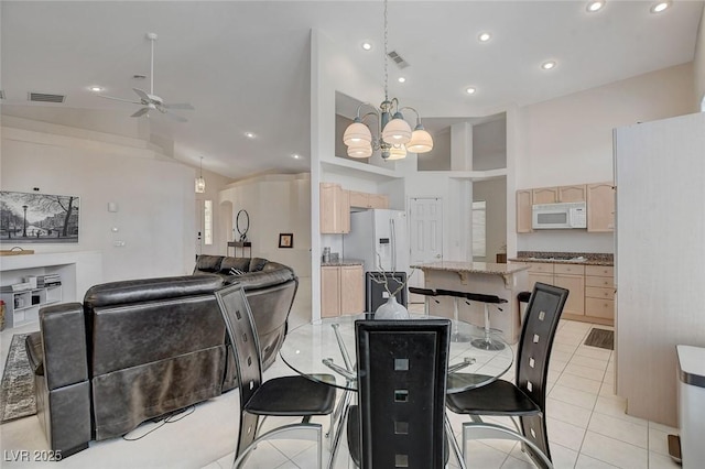 tiled dining space featuring ceiling fan with notable chandelier and high vaulted ceiling