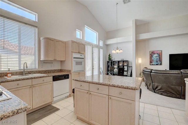 kitchen with white appliances, sink, decorative light fixtures, a kitchen island, and light tile patterned flooring