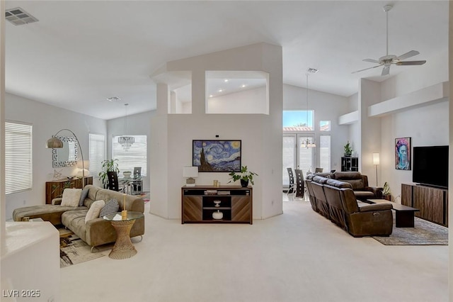 living room with ceiling fan with notable chandelier, carpet flooring, and high vaulted ceiling