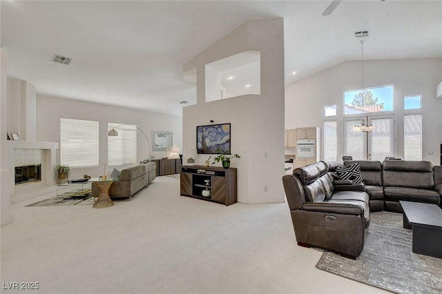 carpeted living room with a fireplace, a chandelier, and high vaulted ceiling