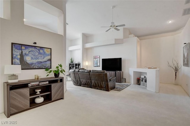 carpeted living room with ceiling fan and a high ceiling