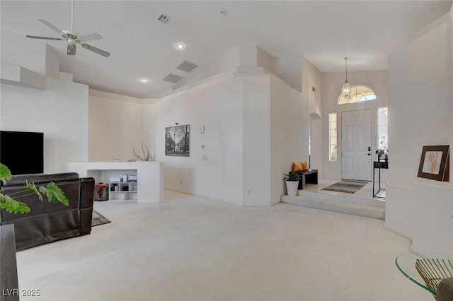 carpeted foyer featuring a towering ceiling and ceiling fan