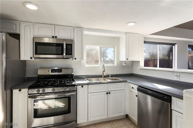 kitchen with light tile patterned floors, appliances with stainless steel finishes, white cabinetry, and sink