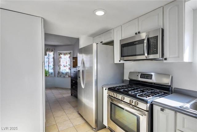 kitchen with white cabinets, appliances with stainless steel finishes, sink, and light tile patterned floors