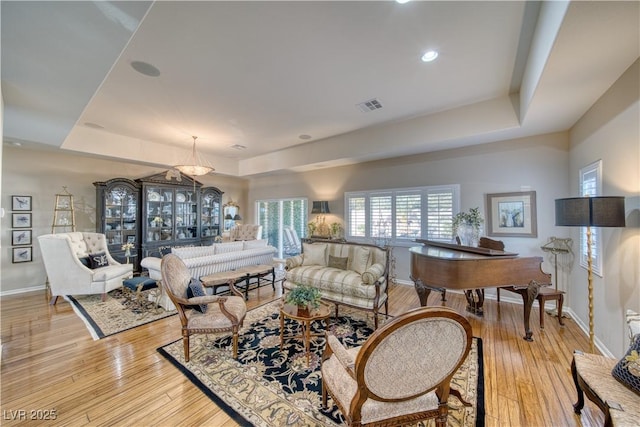 living room featuring a raised ceiling and light hardwood / wood-style flooring