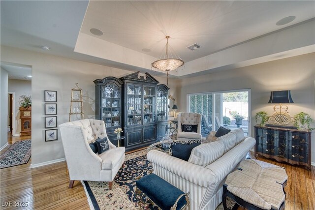 living room with hardwood / wood-style floors and a raised ceiling