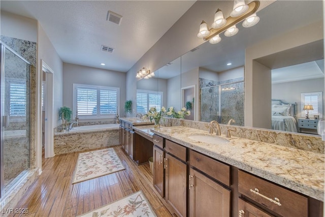 bathroom with vanity, separate shower and tub, hardwood / wood-style floors, and a textured ceiling