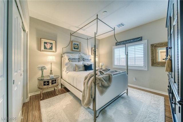 bedroom with visible vents, dark wood finished floors, and baseboards