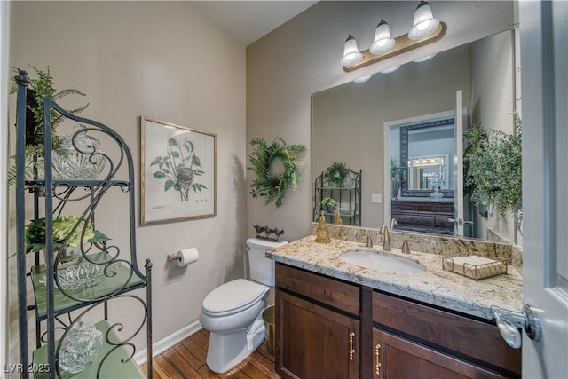 bathroom with vanity, wood finished floors, toilet, and baseboards