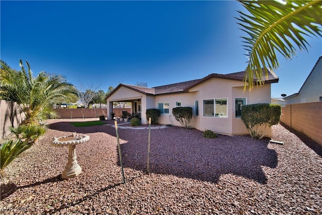 view of front of house with a patio area, a fenced backyard, and stucco siding