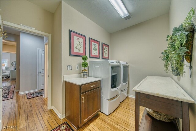 laundry area with washing machine and dryer and light hardwood / wood-style flooring