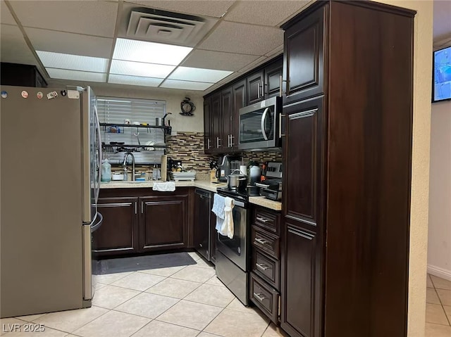 kitchen featuring light tile patterned floors, stainless steel appliances, decorative backsplash, a paneled ceiling, and sink