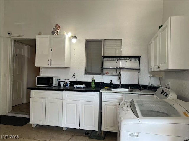 kitchen featuring sink, washer and dryer, and white cabinetry