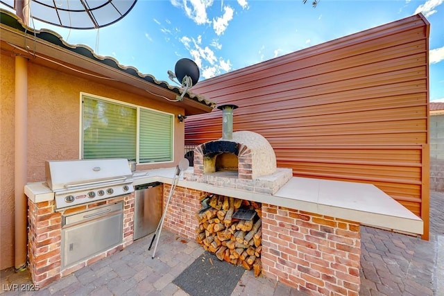 view of patio with a grill, area for grilling, and a fireplace