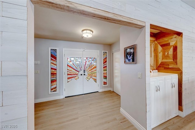 interior space with beam ceiling, french doors, and light hardwood / wood-style floors