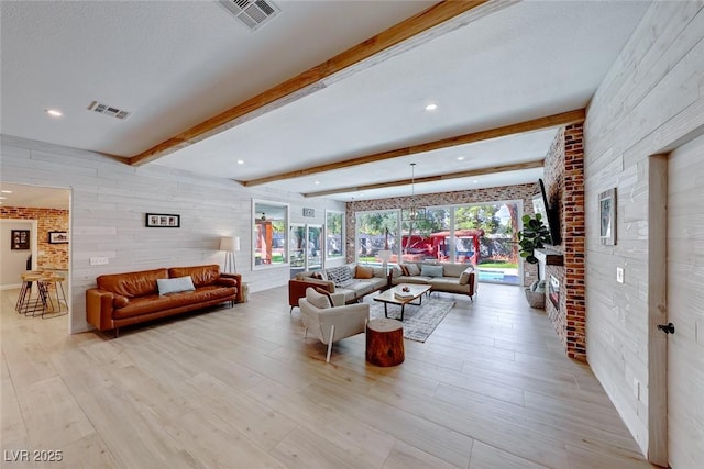 living room with light wood-type flooring, brick wall, a textured ceiling, and beam ceiling