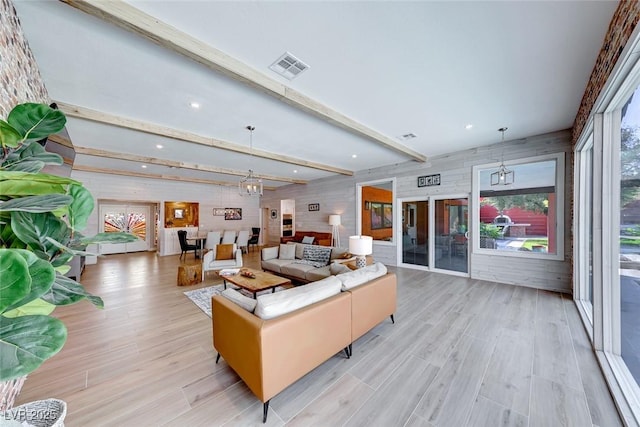 living room featuring light hardwood / wood-style floors, beam ceiling, and a notable chandelier