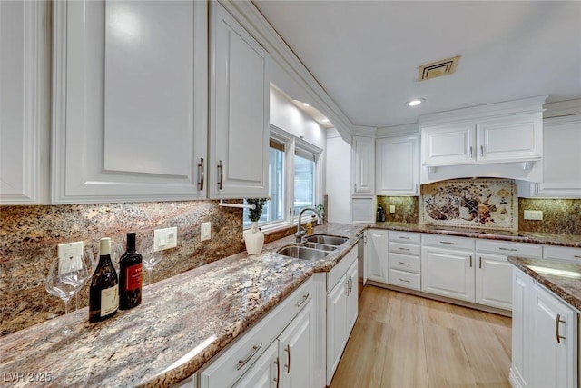 kitchen featuring light stone counters, sink, white cabinetry, and black electric stovetop