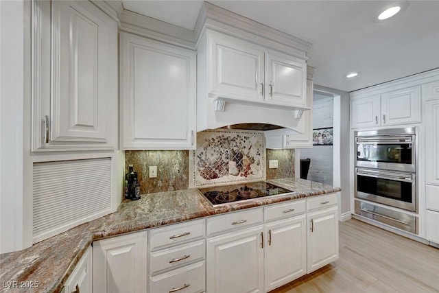 kitchen with black electric stovetop and white cabinetry