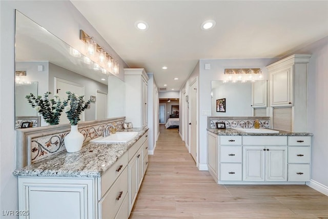 kitchen with white cabinets, light stone counters, backsplash, and sink