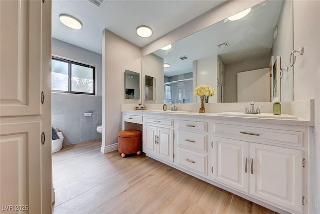 bathroom with toilet, vanity, wood-type flooring, and a shower with shower door