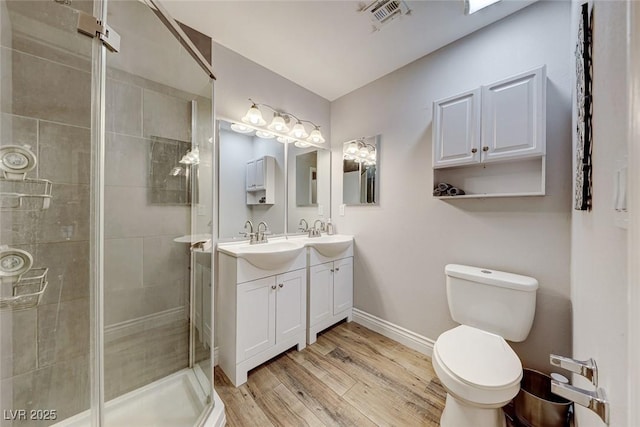 bathroom featuring toilet, vanity, a shower with door, and hardwood / wood-style floors