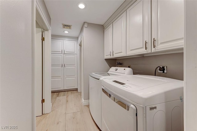 washroom featuring cabinets, separate washer and dryer, and light hardwood / wood-style flooring