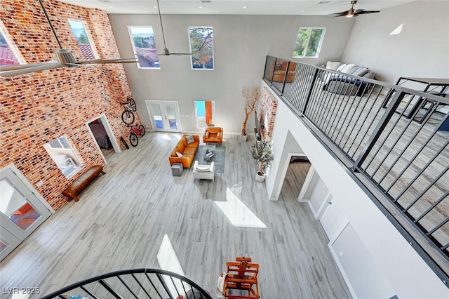 living room featuring ceiling fan, a towering ceiling, and light hardwood / wood-style flooring