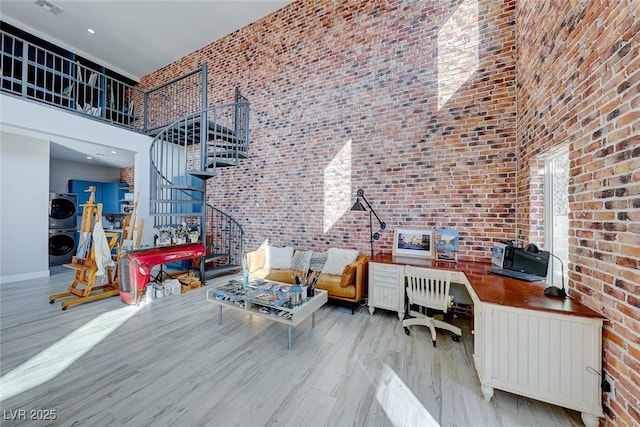 office space featuring stacked washer / drying machine, a towering ceiling, and light wood-type flooring