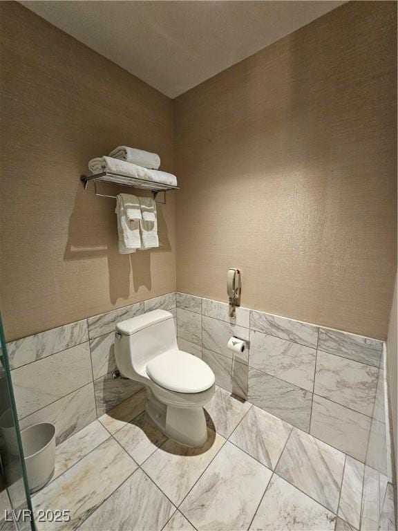 bathroom featuring toilet and tile walls