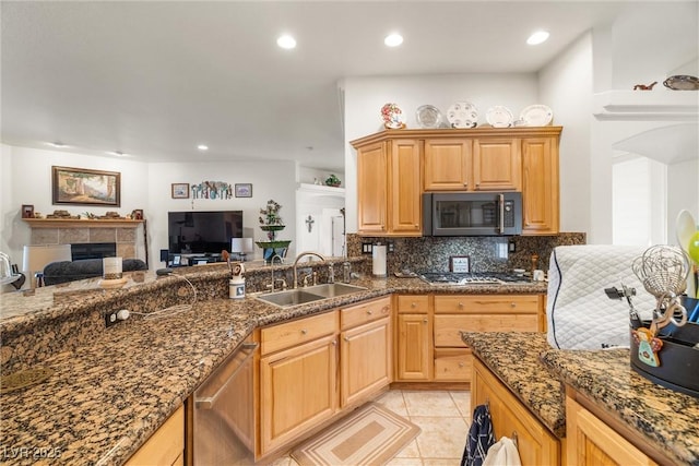 kitchen featuring light tile patterned floors, appliances with stainless steel finishes, tasteful backsplash, a fireplace, and sink