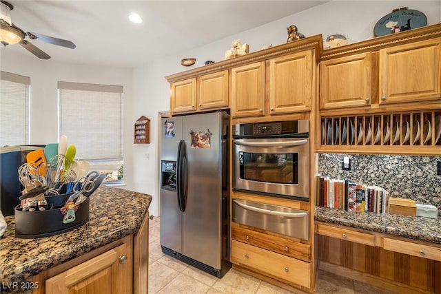 kitchen with ceiling fan, backsplash, dark stone countertops, stainless steel appliances, and light tile patterned floors