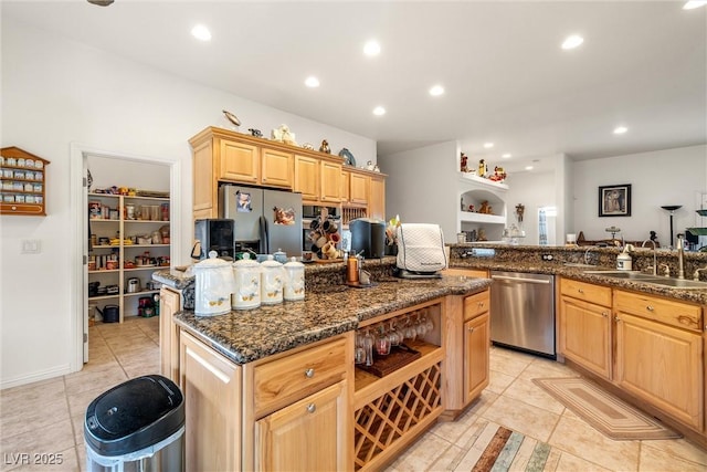 kitchen with dark stone countertops, a center island, sink, appliances with stainless steel finishes, and light brown cabinetry