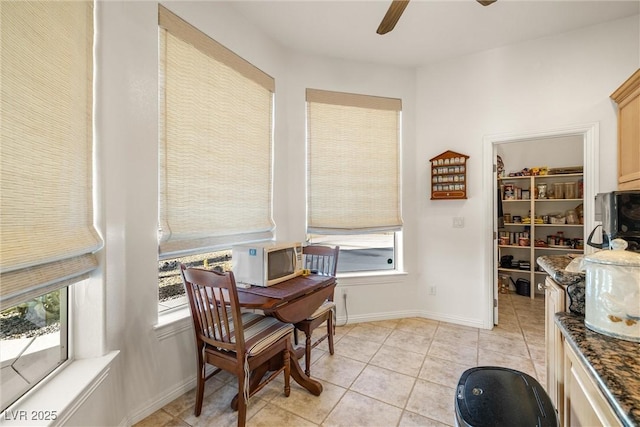 living area featuring ceiling fan, light tile patterned flooring, and a healthy amount of sunlight