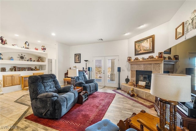 living room featuring french doors, a tile fireplace, and built in shelves