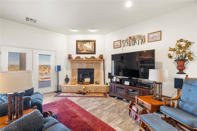 living room featuring french doors, wood-type flooring, and a tiled fireplace