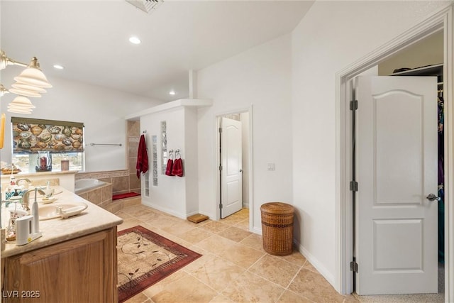 bathroom featuring tiled tub and vanity