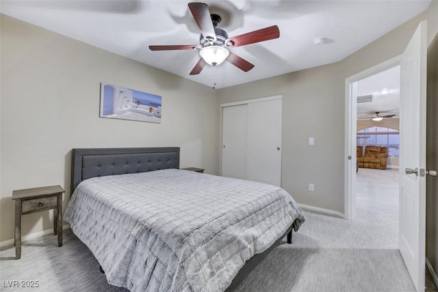 carpeted bedroom with ceiling fan and a closet