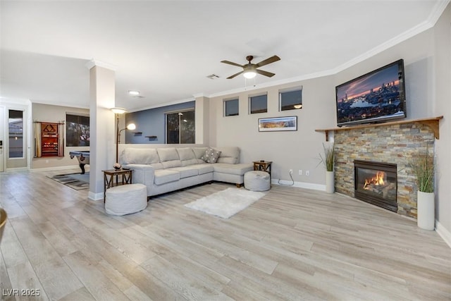 living room featuring ceiling fan, a fireplace, crown molding, and light hardwood / wood-style flooring