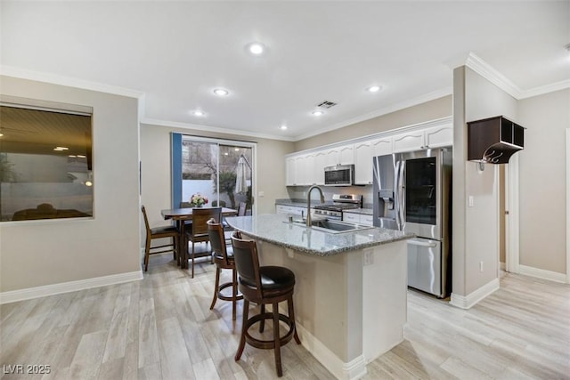 kitchen with light hardwood / wood-style floors, white cabinetry, appliances with stainless steel finishes, and ornamental molding