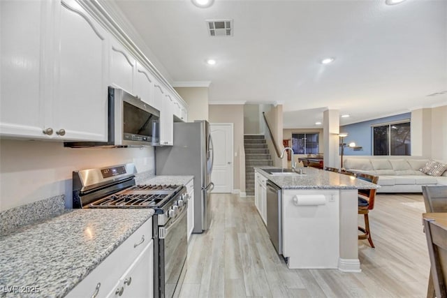 kitchen with appliances with stainless steel finishes, sink, white cabinetry, and ornamental molding