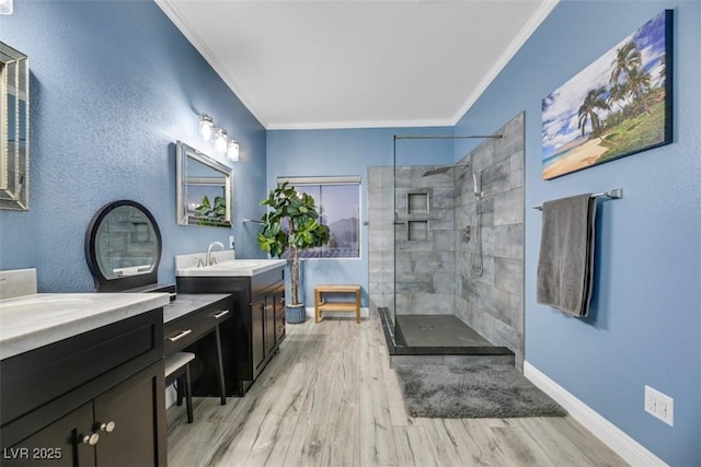 bathroom with vanity, wood-type flooring, crown molding, and a tile shower