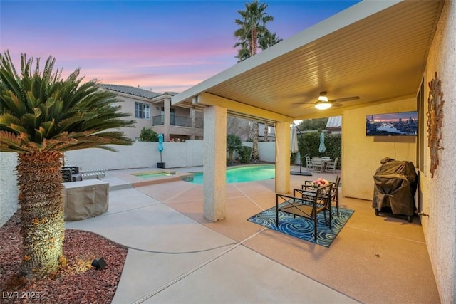 patio terrace at dusk with ceiling fan and a fenced in pool