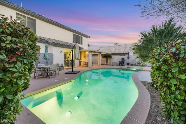 pool at dusk with a patio area